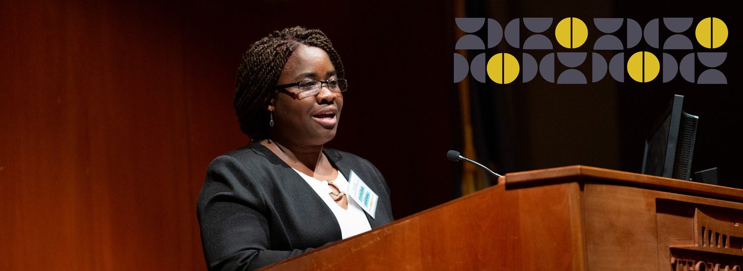 A woman, Dr. Fiona Vernal, gives a speech at a podium in the Konover Auditorium at The Dodd Center for Human Rights.