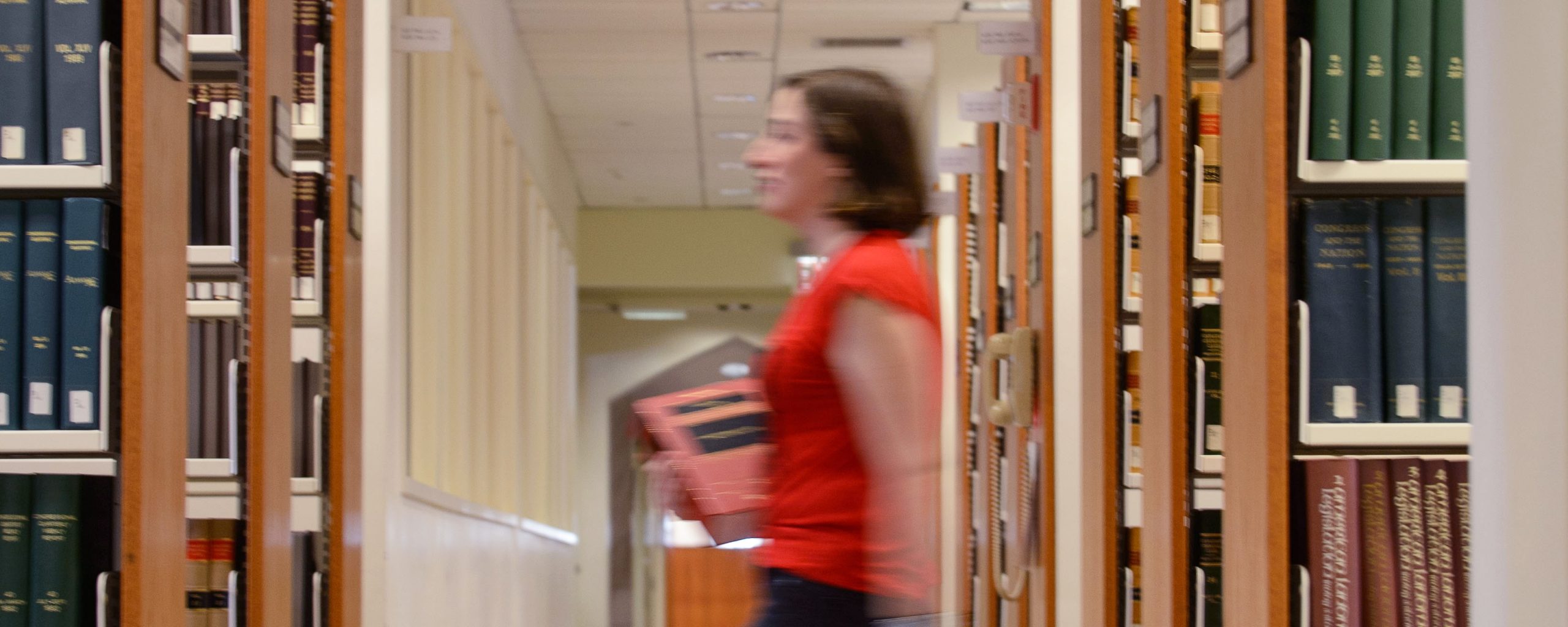 Student walks through the library stacks.