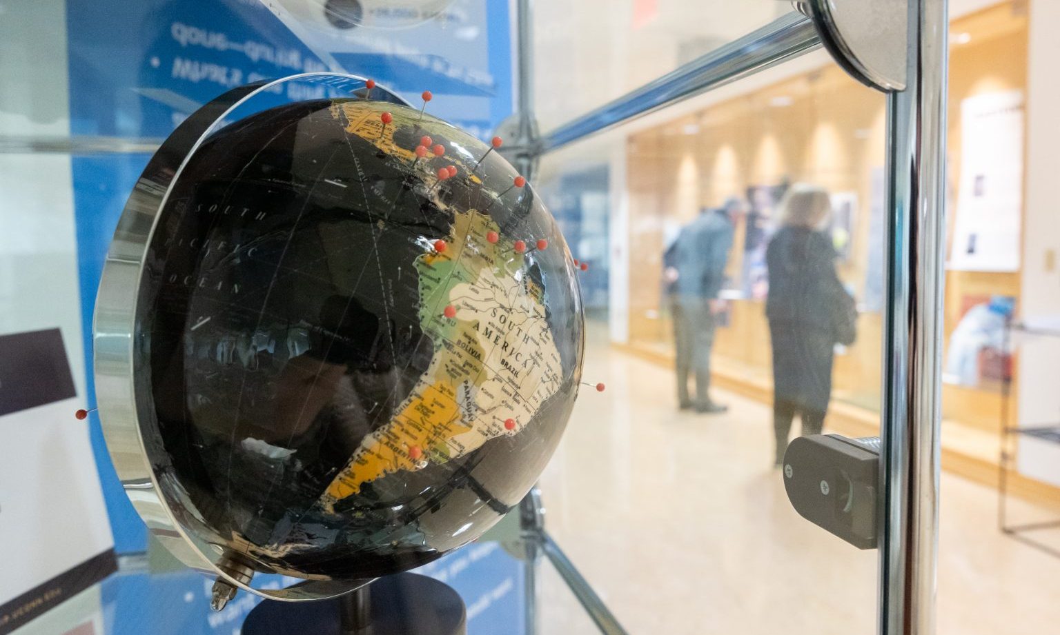 A globe within a display case is marked with red pins. 