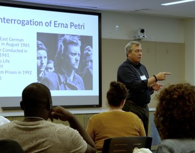 Director pf the Dodd Human Rights Impact Programs, James Waller leads a presentation. The slide on the projector reads "Interrogation of Erna Petri."