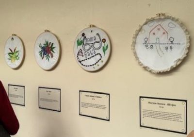 A photo of an exhibit shows four circular pieces of art and a label under each.  